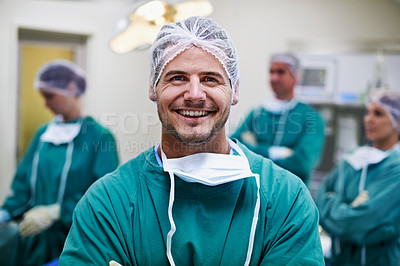 Buy stock photo Portrait of a confident doctor in the operating room with his surgical team in the background