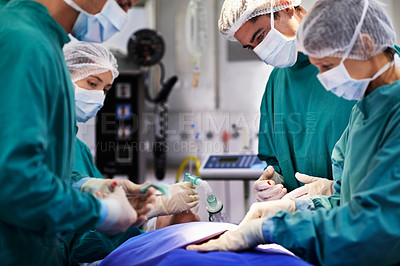 Buy stock photo Shot of a team of surgeons performing an operation