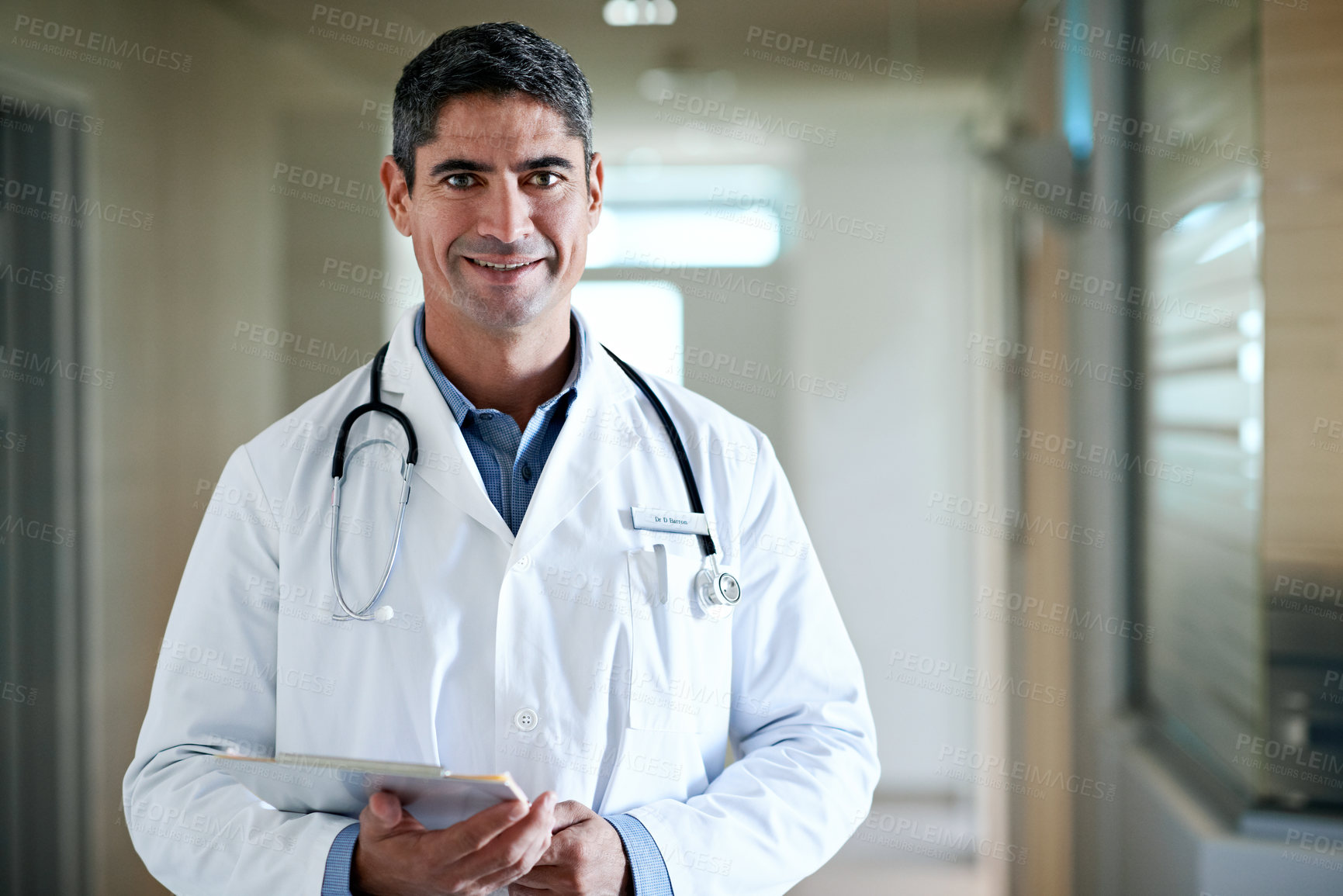 Buy stock photo Doctor, portrait and happy man with clipboard in hospital hallway for medical service or healthcare. Male person, health worker or professional with smile for medicare, assistance or advice in clinic