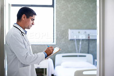 Buy stock photo Shot of a doctor taking down notes in a hospital