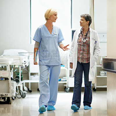 Buy stock photo Shot of two doctors having a discussion in a hospital corridor