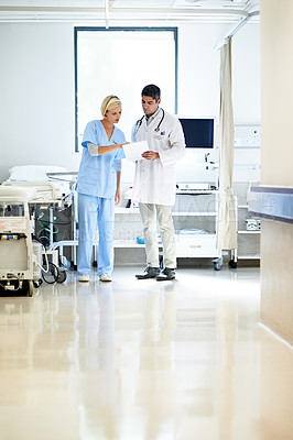 Buy stock photo Shot of two doctors having a discussion in a hospital corridor