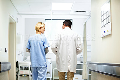 Buy stock photo Rearview shot of two doctors having a discussion in a hospital corridor