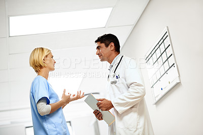 Buy stock photo Shot of two doctors having a discussion in a hospital corridor