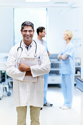 Buy stock photo Portrait of a confident doctor with medical staff in the background
