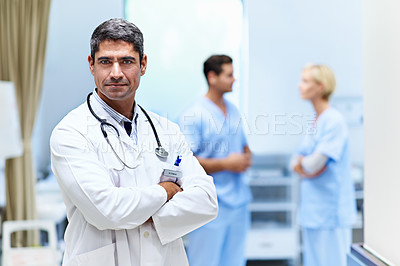 Buy stock photo Portrait of a confident doctor with medical staff in the background