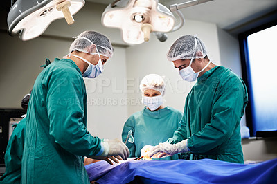 Buy stock photo Shot of a team of surgeons performing an operation