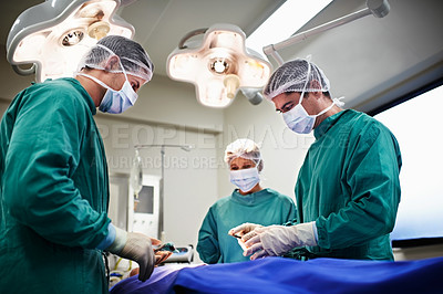Buy stock photo Shot of a team of surgeons performing an operation