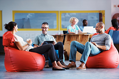 Buy stock photo Full length shot of businesspeople sitting on beanbag chairs in the office