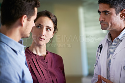 Buy stock photo Shot of a doctor delivering news to a couple in a hospital waiting room
