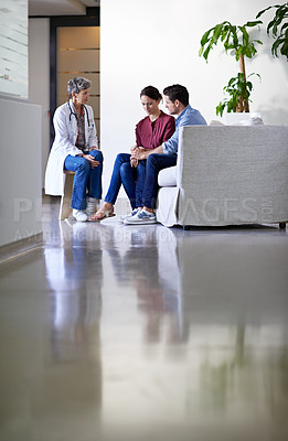 Buy stock photo Shot of a doctor delivering news to a couple in a hospital waiting room