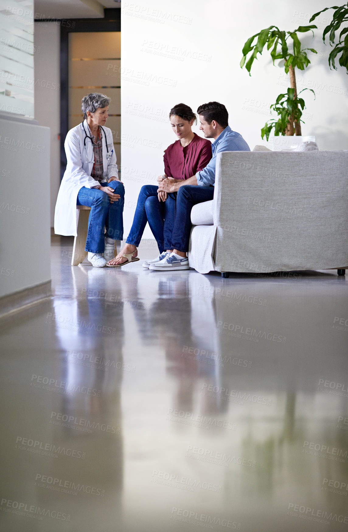 Buy stock photo Shot of a doctor delivering news to a couple in a hospital waiting room