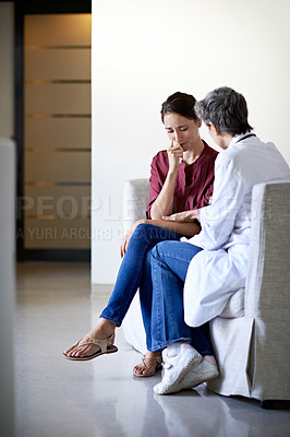 Buy stock photo Shot of a compassionate doctor comforting a young woman in a hospital waiting room
