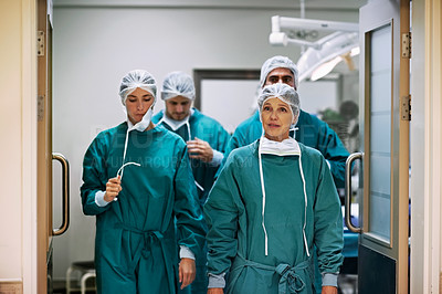 Buy stock photo Shot of a group of surgeons walking down a hospital corridor