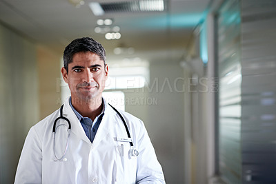 Buy stock photo Portrait of a mature male doctor standing in a hospital corridor