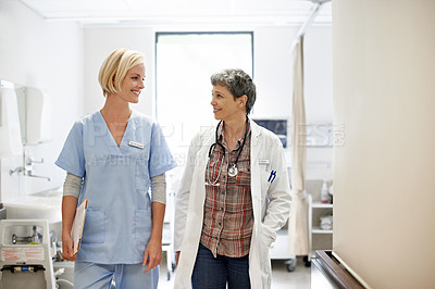 Buy stock photo Shot of two female doctors walking down a hospital corridor