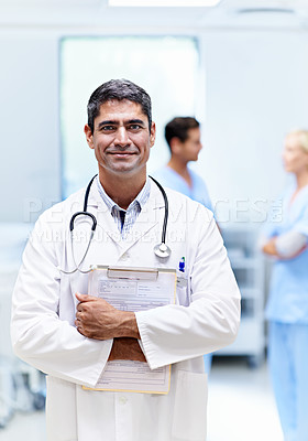 Buy stock photo Portrait of a male doctor with colleagues in the background