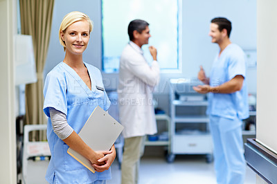 Buy stock photo Portrait of a young female doctor with colleagues in the background