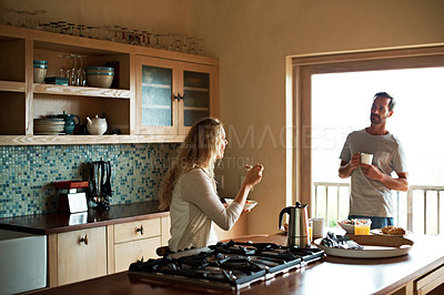 Buy stock photo Shot of a couple having a conversation while having breakfast in the kitchen