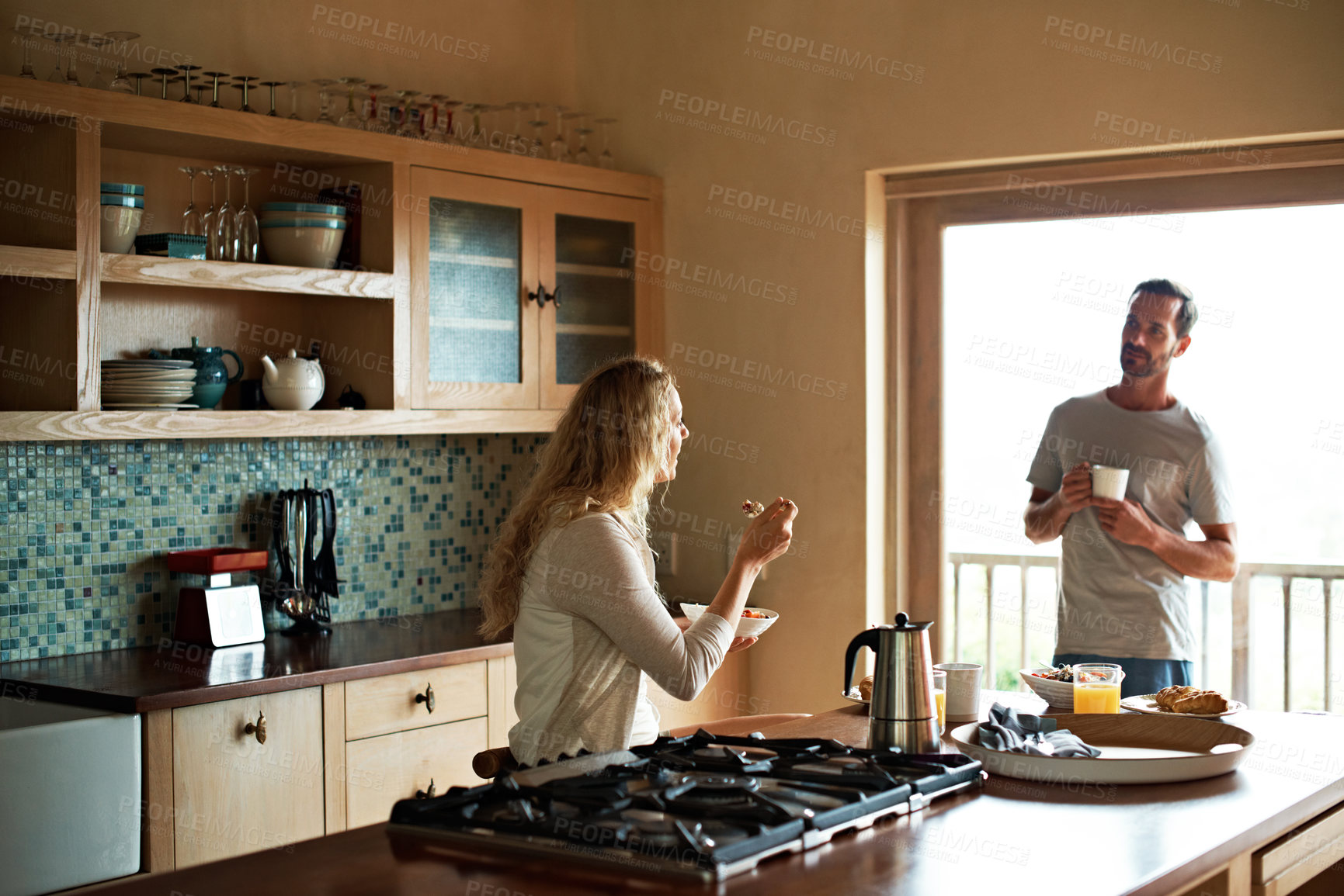 Buy stock photo Shot of a couple having a conversation while having breakfast in the kitchen