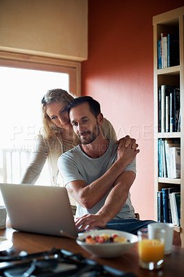Buy stock photo Shot of a woman standing behind her husband who's using his laptop