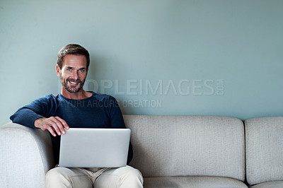 Buy stock photo Portrait of a man using his laptop while relaxing at home