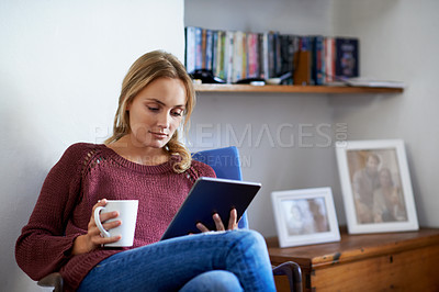 Buy stock photo Shot of a young woman using a digital tablet while relaxing at home