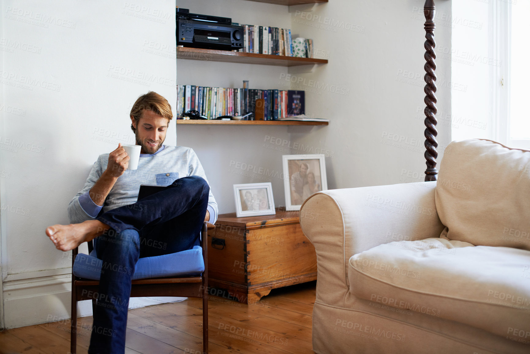 Buy stock photo Shot of a man using a digital tablet while relaxing at home