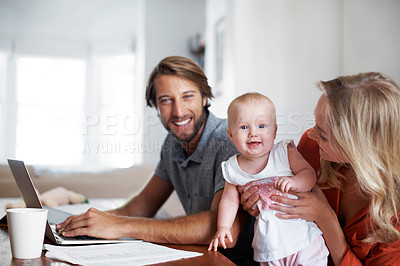 Buy stock photo Shot of a man using a laptop with his wife and baby girl next to him
