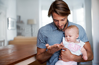 Buy stock photo Shot of a smiling father playing with his baby girl at home