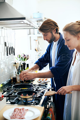 Buy stock photo Shot of a young couple cooking together in the kitchen