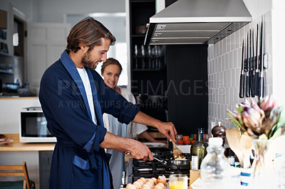 Buy stock photo Shot of a young couple cooking together in the kitchen