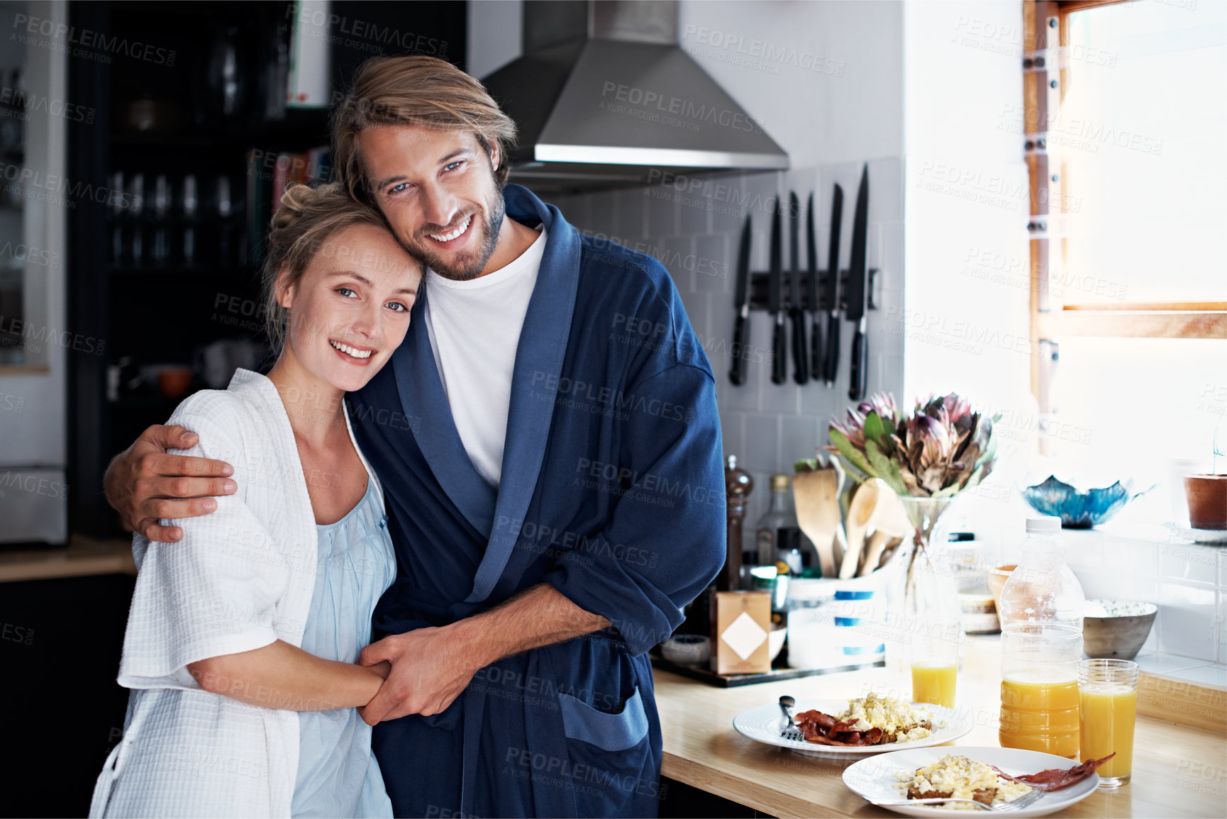 Buy stock photo Portrait of a young couple standing in the kitchen while cooking breakfast