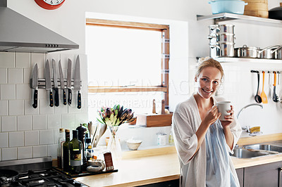 Buy stock photo Portrait of a young woman having her morning coffee in the kitchen