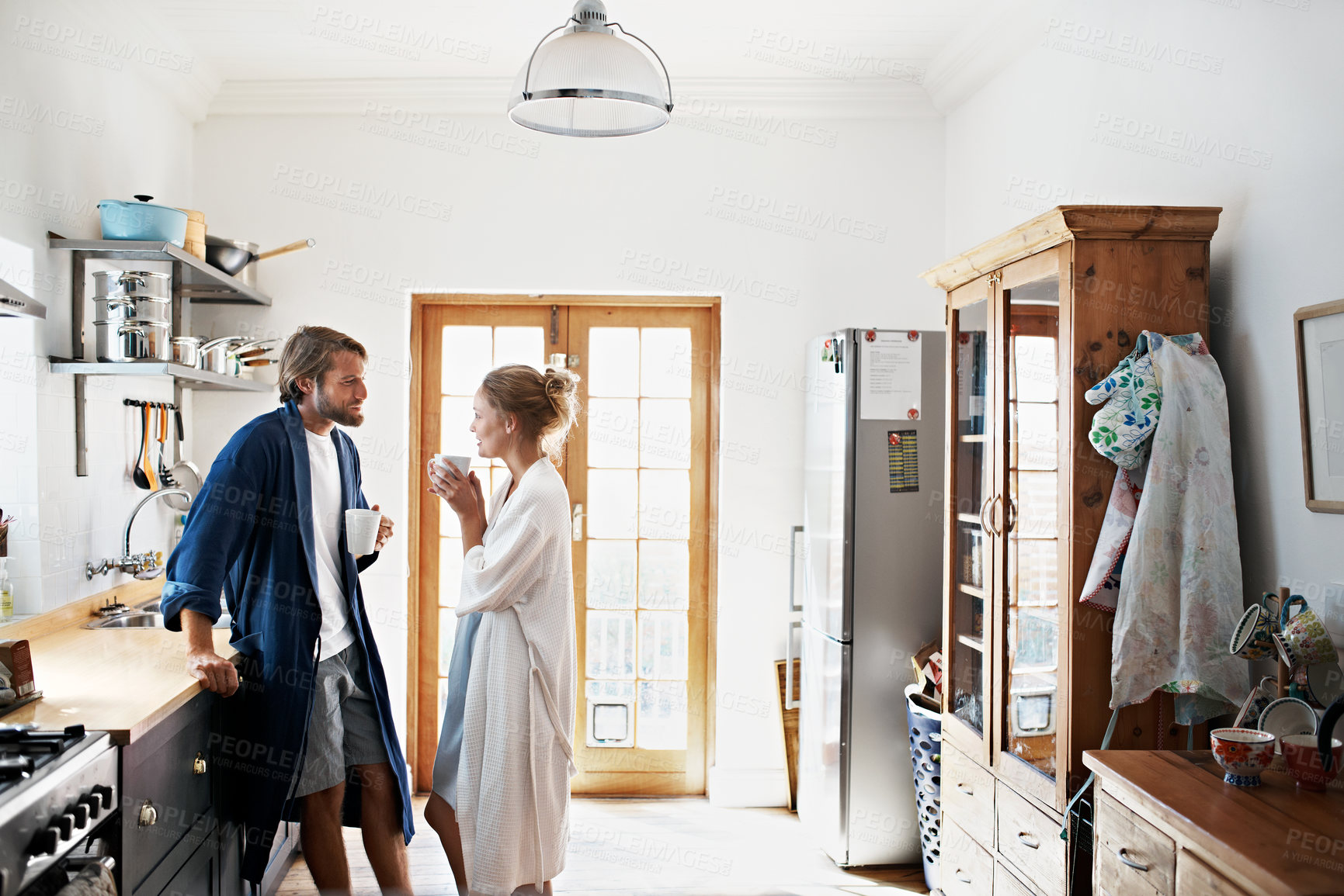 Buy stock photo Shot of a young couple standing together drinking coffee in the kitchen