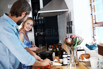 Buy stock photo Shot of a young couple cooking together in the kitchen