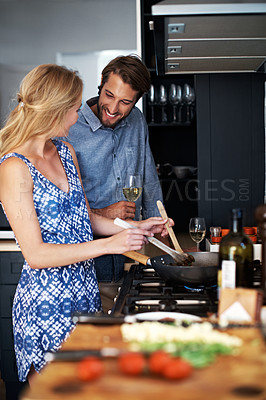 Buy stock photo Shot of a young couple cooking together in the kitchen