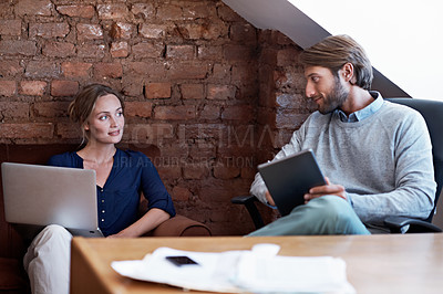 Buy stock photo Shot of a young couple using a digital tablet and laptop while relaxing at home