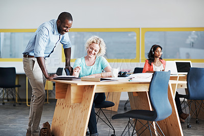 Buy stock photo Shot of a man assisting his coworker with their colleague blurred in the background