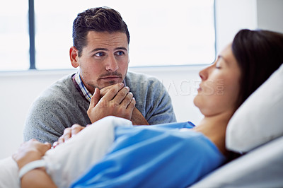 Buy stock photo Shot of a woman lying in a hospital bed being comforted by her husband