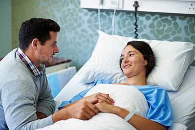 Buy stock photo Shot of a woman lying in a hospital bed being comforted by her husband