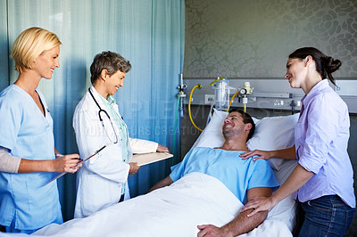 Buy stock photo Shot of a doctors talking to a male patient lying in a hospital bed