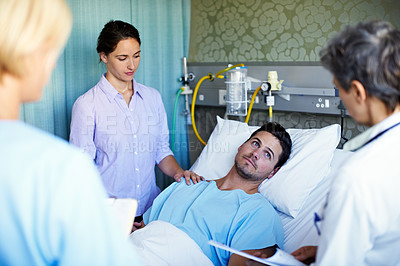 Buy stock photo Shot of a doctors talking to a male patient lying in a hospital bed