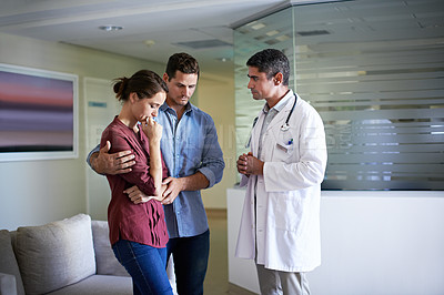 Buy stock photo Shot of a doctor talking to a grieving woman and her husband in a hospital waiting room