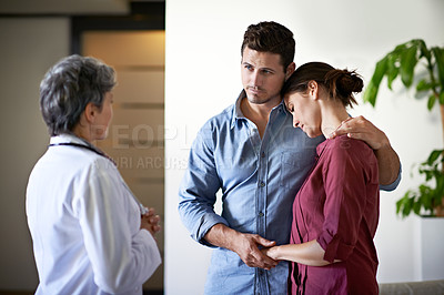 Buy stock photo Shot of a doctor talking to a husband comforting his wife in a hospital waiting room