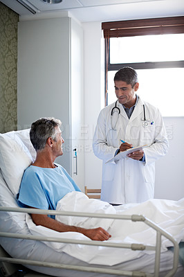 Buy stock photo Shot of a doctor having a conversation with a patient lying in a hospital bed