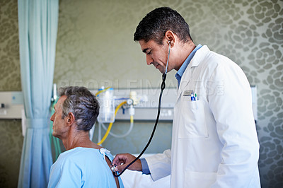 Buy stock photo Shot of a doctor doing tests on a patient sitting on a hospital bed