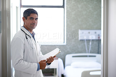 Buy stock photo Portrait of a male doctor standing in a ward holding paperwork