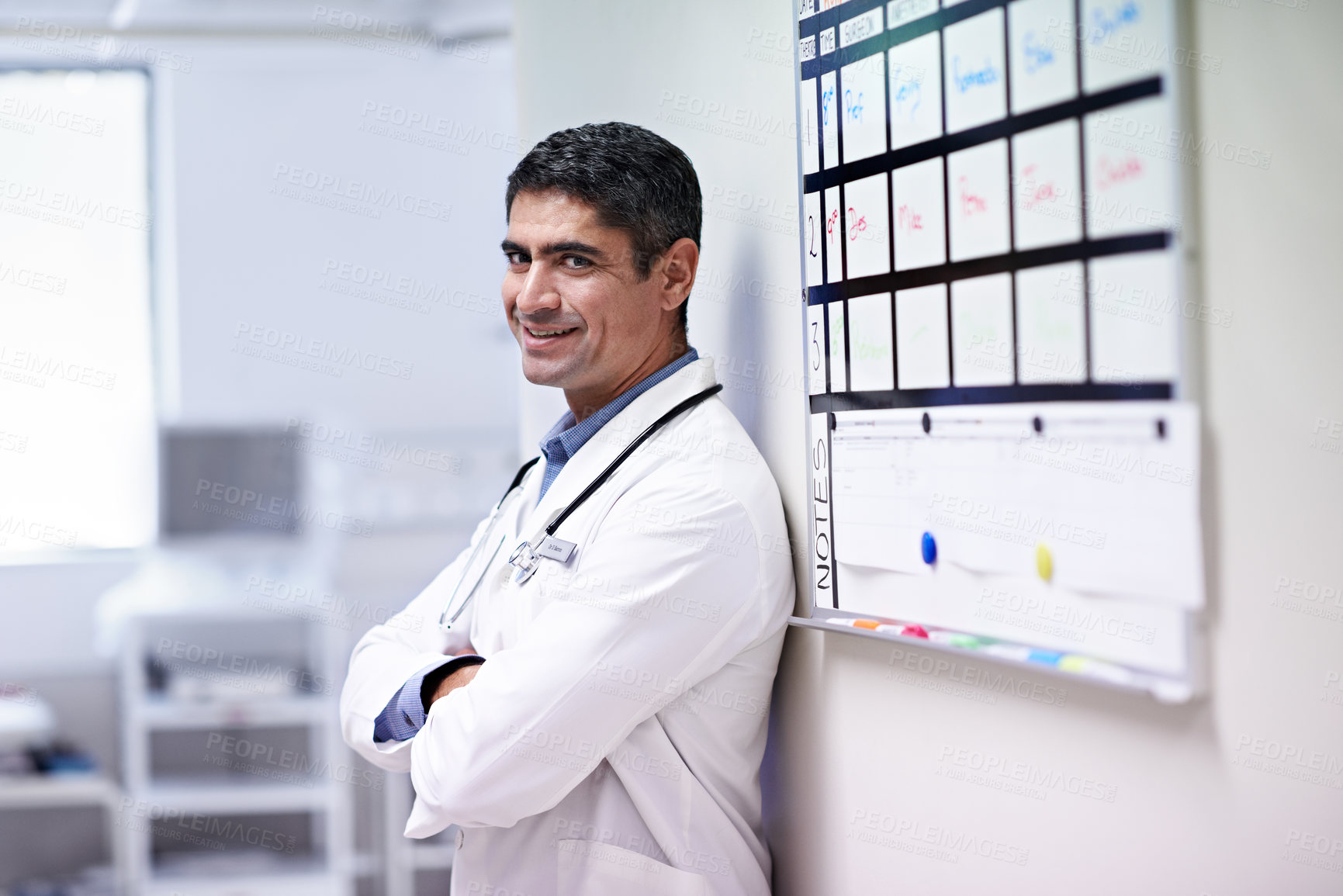 Buy stock photo Confident, doctor and man with arms crossed in hallway, health services or smile with career growth. Clinic, healthcare professional and happy person with medical duty, portrait and wellness job