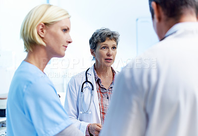 Buy stock photo Shot of a team of doctors having a discussion in a hospital